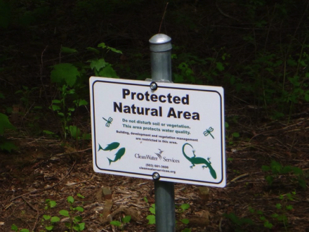Sign - protected natural area - do not disturb soil or vegetation - this area protects water quality